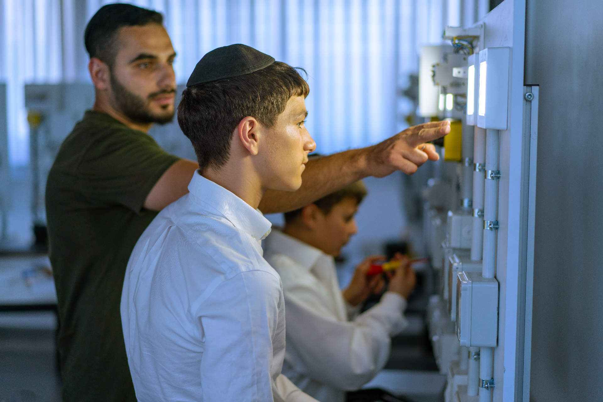 תלמידים בעבודה מעשית על לוח חשמל
